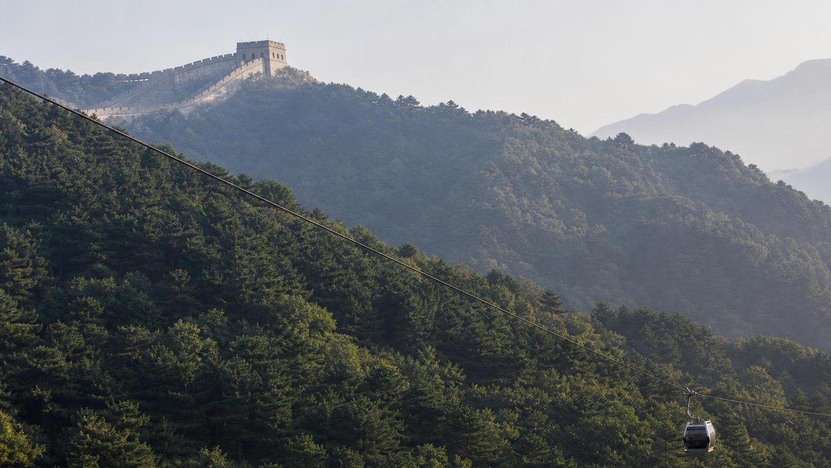 Forested Great Wall route with an enclosed cable car illustrating Mutianyu's visitor options.