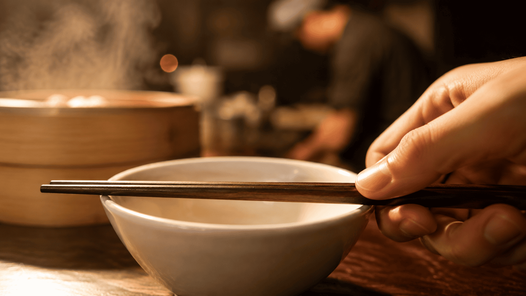 Close-up of chopsticks resting on a ceramic bowl
