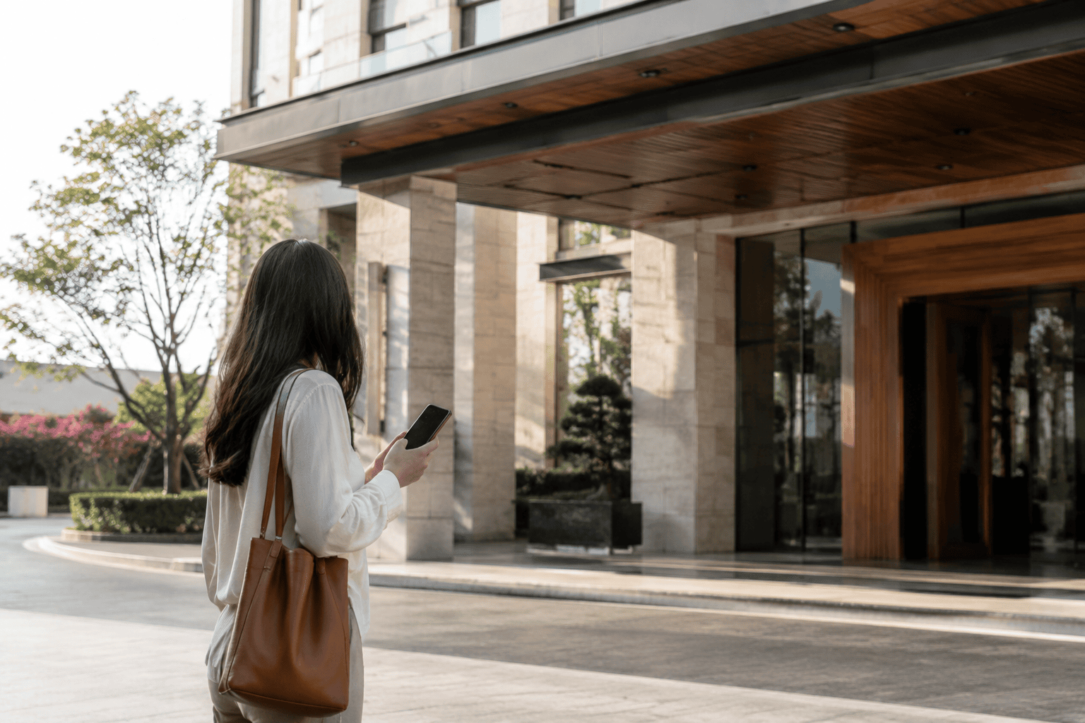 Traveler confirming a hotel entrance beside a bright stone drop-off area